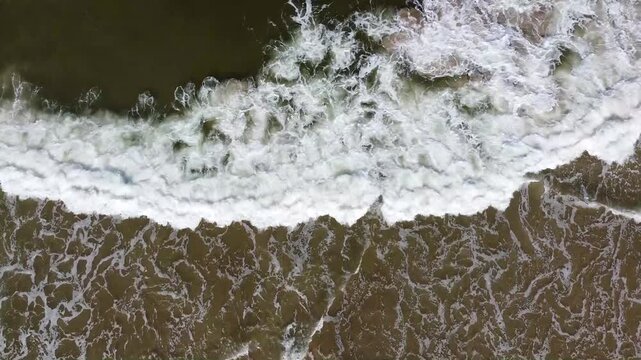 Olas rompiendo en la arena de la playa con mucha espuma