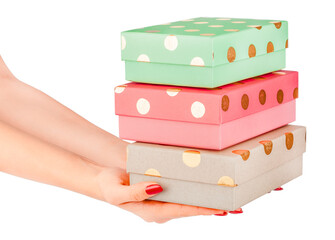 Female hands holding a stack of three colorful gift boxes with gold polka dots pastel green, pink, and beige packages isolated festive and cheerful concept birthday, Christmas celebration.