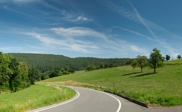 road in the countryside with cirrus clouds in the blue sky
