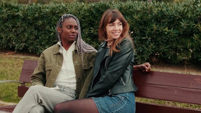 Two female friends or couple enjoy a relaxing moment in a park. This video evokes feelings of happiness and friendship during the autumn season.