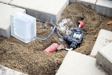Ground-level electrical box installation with exposed cables during construction process on paved area. Use for electrical engineering, urban infrastructure, maintenance systems . Real photo