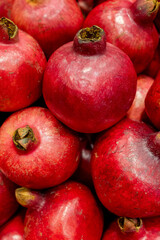 Fresh red pomegranates stacked in grocery market close-up