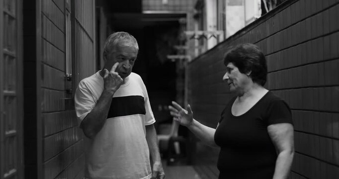 Elderly couple in heated confrontation, woman pointing accusingly while man stands defensively, dramatic black and white moment of emotional tension and disagreement