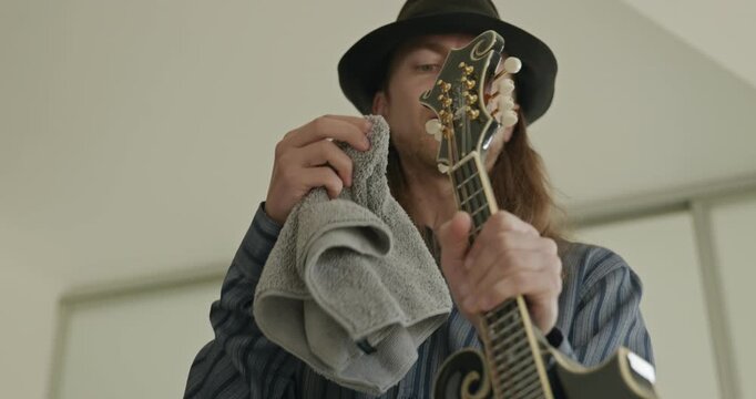 Male Musician Diligently Take Care of Instrument. Wipe Dust from Mandolin 4K 10-bit