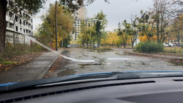 An autumn cityscape through a cracked car windshield &mdash; rain, wet roads, fallen leaves, and an atmosphere of anticipation and vulnerability.