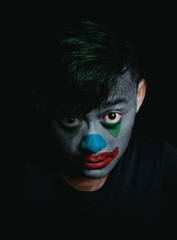 Dramatic Portrait of an Asian Young Man with Dark Clown Makeup on Black Background. Conveying a moody, dramatic, and sinister theme.