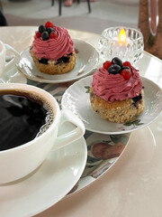 Cupcake with pink raspberry cream on a white plate. Photo