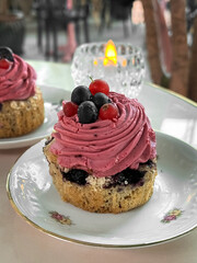Cupcake with pink raspberry cream on a white plate. Photo