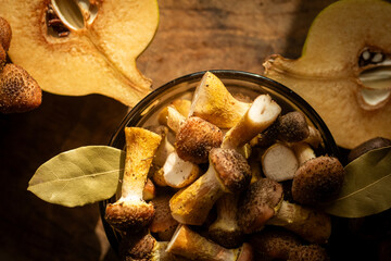 Honey mushrooms with bay leaves and quince on a rustic wooden table