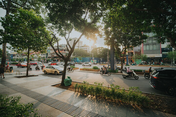 Sunlit Urban Street with Motorbikes and Trees in Ho Chi Minh City, Vietnam