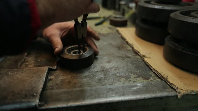 Skilled worker adjusts and maintains complex vintage printing press or typesetting machine. Detailed close-up of hands on intricate industrial components and levers.