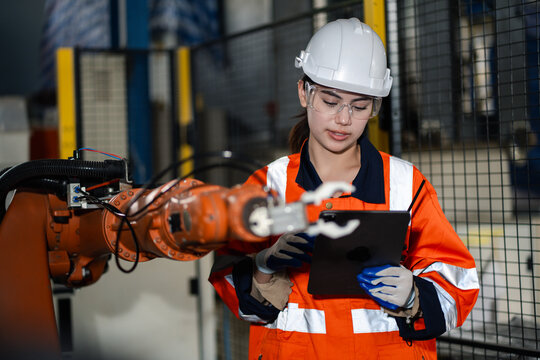 Portrait of smiling female engineer in safety gear holding tablet at industrial site. Concept of women in engineering, industrial technology, safety, innovation, and professional workplace. - Powered by Adobe