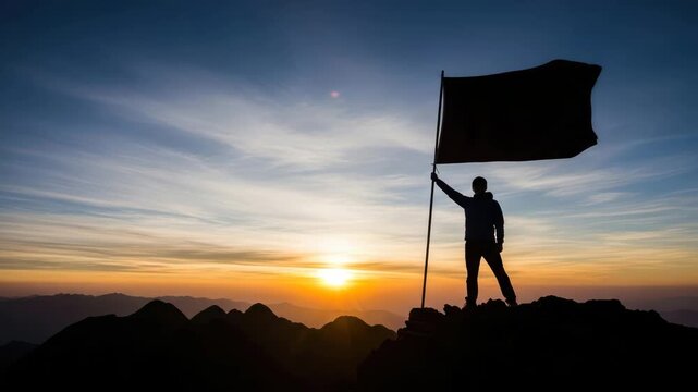 Silhouette of a person holding a flag on top of a mountain at sunset