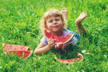 Child eats watermelon in summer. Selective focus.
