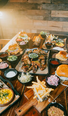A table full of food including a plate of chicken wings, a plate of fries