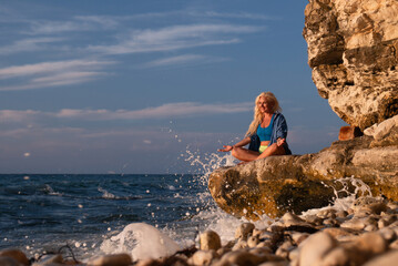 Woman Yoga Cliff Ocean - Woman meditating on a cliff overlooking the ocean with waves crashing.