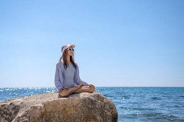 Meditation Woman Sea, young woman meditating on large rock by ocean sunny day for relaxation.