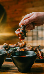 A person is eating a piece of chicken with barbecue sauce