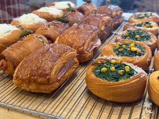 Savory croissants and pastries with spinach and corn in bakery display. Texture, flavor, and...