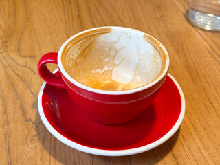 Empty cappuccino cup with foam traces on wooden table. Relaxation, warmth and everyday coffee ritual in cozy cafe setting.