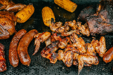 A variety of meats and vegetables are being cooked on a grill