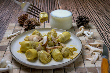 Plate of cooked artichokes with fresh mushrooms served on a rustic background, perfect for healthy cooking and autumn cuisine