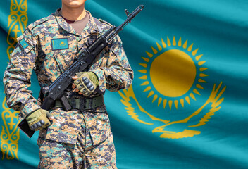 Fototapeta premium Kazakhstan flag with soldier in military uniform holding assault rifle in front of it