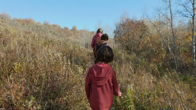 Woman and two children hiking along a trail in a park on a sunny day