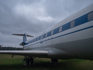 old plane scene, vintage airplane with blue stripe on runway, classic long aircraft with polished fuselage and windows, side view of vintage airliner featuring blue stripe and multiple