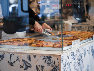 Poznan Poland - 19.10.2025: Employee preparing and packaging pastel de nata custard tarts inside pastry cafe