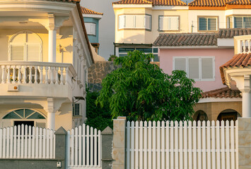 Mediterranean-style houses in Bella Vista, Gran Canaria, bathed in golden evening sunlight, with tiled roofs, pastel walls, white balconies.