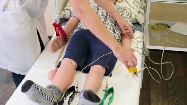 Medical education scene showing a healthcare professional attaching ecg electrodes to a child-sized training dummy, preparing for a heart diagnostics simulation on an examination table in a clinic