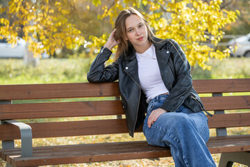 Young beautiful woman sitting on a bench in an autumn park