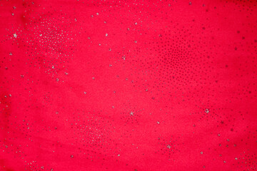 Red glittery fabric background with silver stars and dots for festive design and pattern