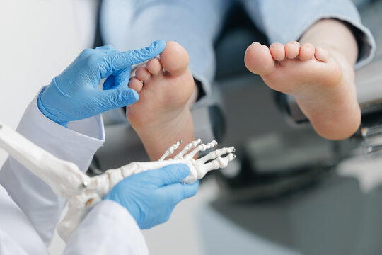 Podiatrist treating feet of female caucasian during procedure, white background.