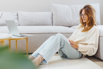 Obraz premium Freelance student engages in online study while relaxing at home in casual attire during daytime
