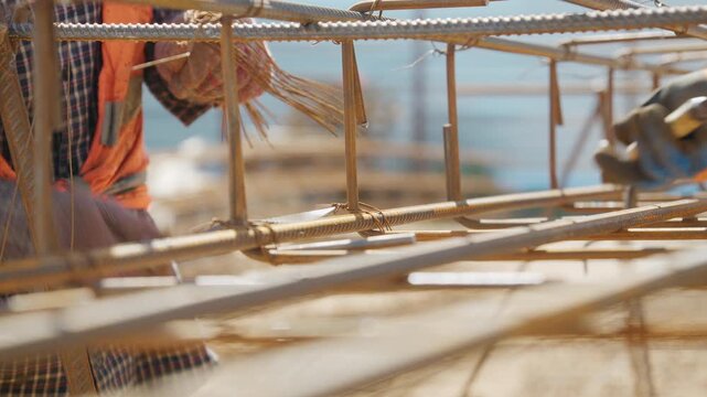 Worker in gloves tying rebar cage at a construction site