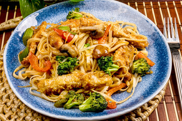A dinner plate  of Asian pork stir fry with bean sprouts and broccoli and mushrooms