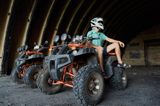 An adventurous individual riding an ATV within the confines of an abandoned warehouse setting - Powered by Adobe