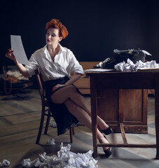 red-haired Woman Writer in a Dramatic Setting with Vintage Typewriter and Crumpled Papers