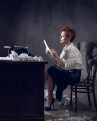 red-haired Woman Writer in a Dramatic Setting with Vintage Typewriter and Crumpled Papers