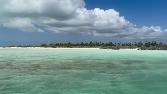 Beautiful 4K footage of the crystal-clear turquoise lagoon and tropical shoreline of Kiritimati (Christmas Island), Kiribati. Gentle waves, white sand, and lush palm trees create a peaceful South Paci