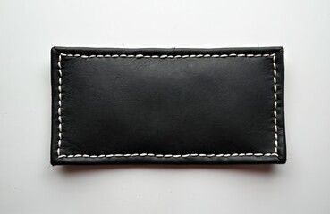 Black rectangular patch with fine white stitching on minimalist white background. Leather material, elegant design suitable for branding, presentation, or business concepts.