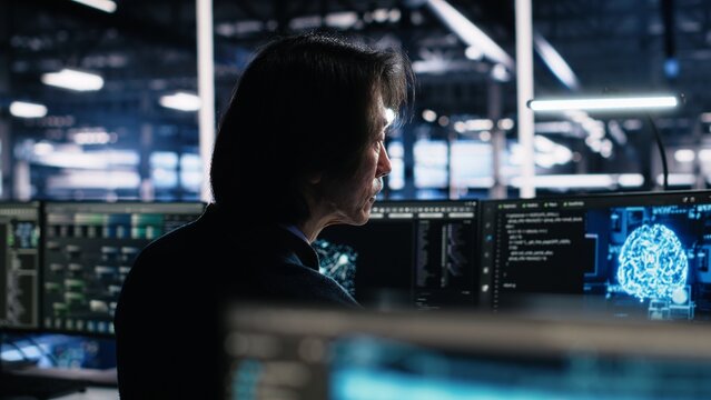 Programmer in data center coding with generative AI assistance. IT professional leveraging artificial intelligence large language model to solve tasks in server room, camera A