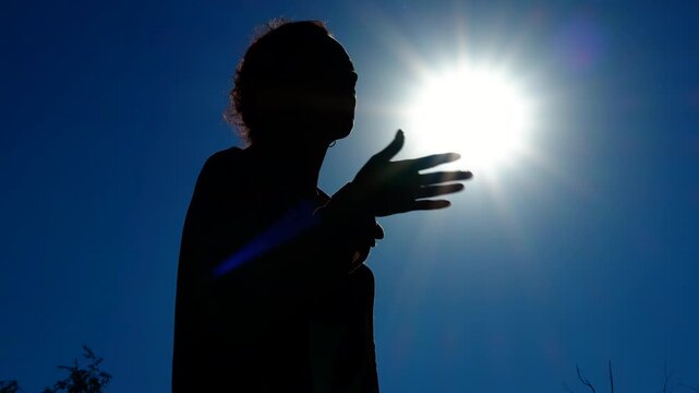 Woman drinking water under the sun silhouette. Woman silhouetted drinking water from plastic bottle, standing under intense sunlight and combating heat hydration during sweltering summer conditions