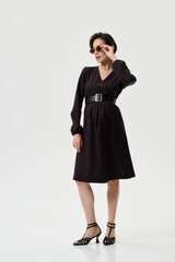 Fototapeta premium A pregnant model girl in stylish clothes poses on a white background.