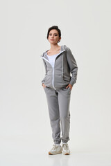 A pregnant model girl in stylish clothes poses on a white background.