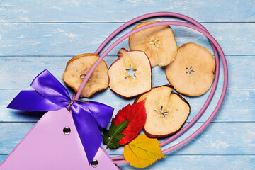 Round dried apple chips and autumn leaves on a wooden background in a paper gift bag