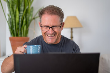 Happy adult man working from home using laptop