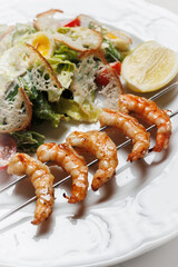 Delicious Caesar Salad with Grilled Shrimp Skewers and Lemon